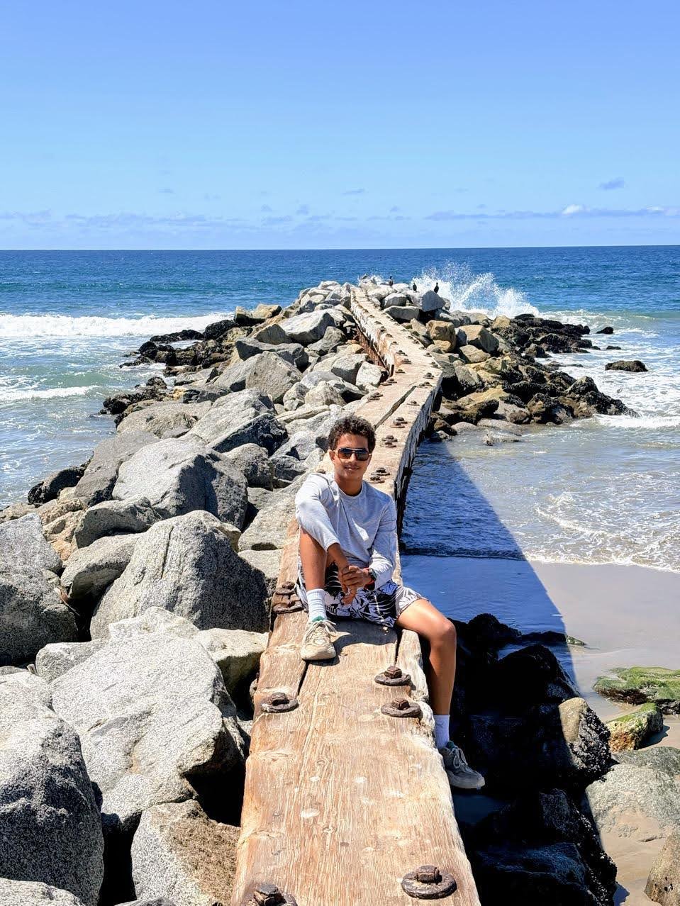 Hrudai sitting on a jetty by the ocean